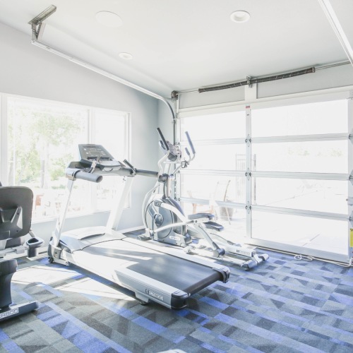 Workout in style in our 24-hour fitness center Fitness center with equipment and garage doors