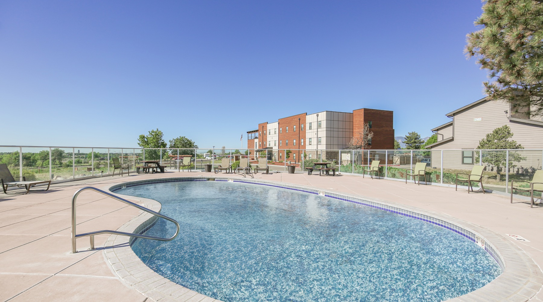 Take a dip in our swimming pool, complete with a sundeck Swimming pool with sundeck and building in the background